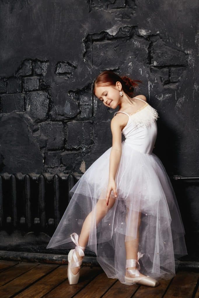 Girl in a white ball gown and shoes, beautiful red hair. Young theater actress